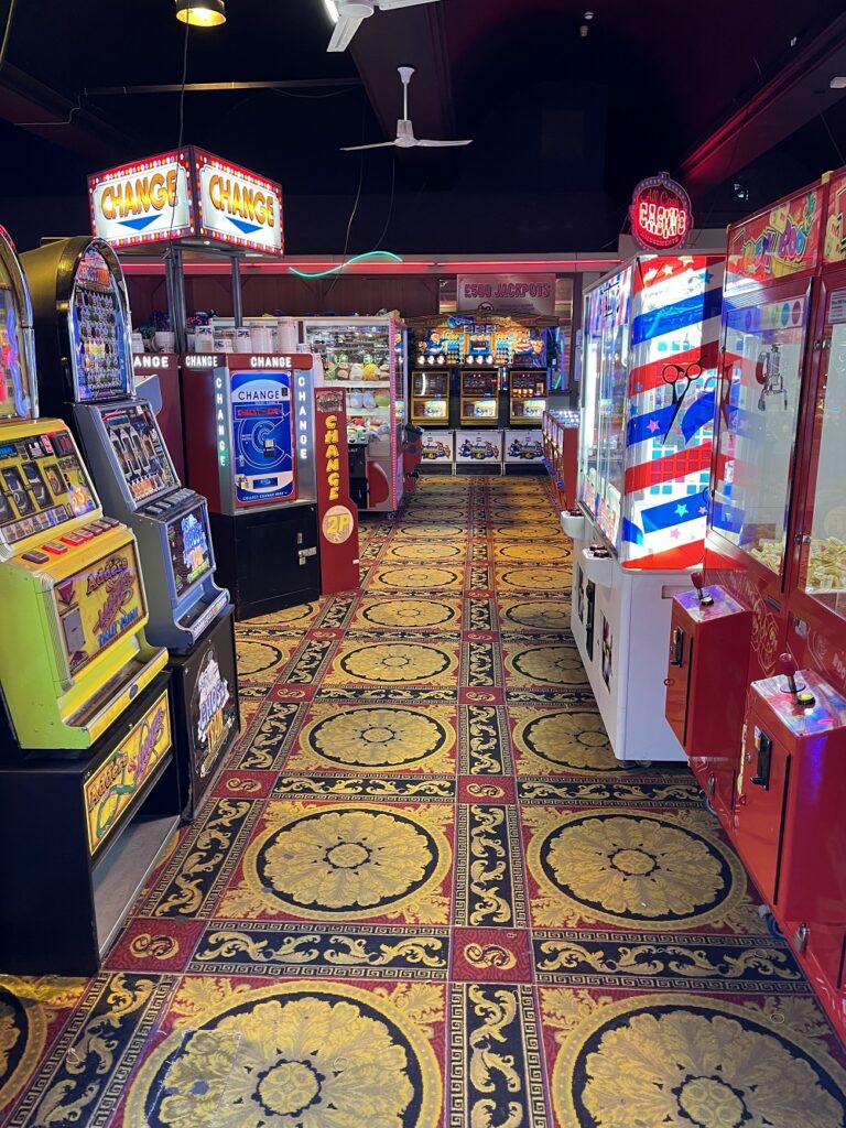 The colourful interior of an amusement arcade with one armed bandits, change machines etc.