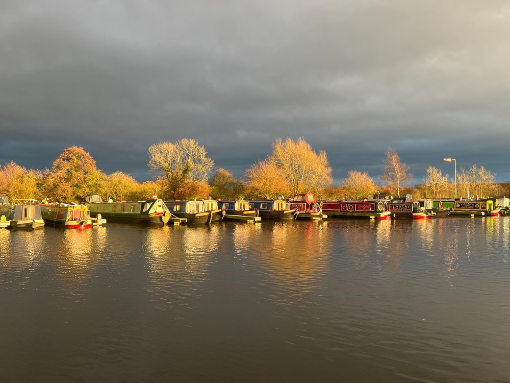 A sunset provides reflections of narrowboats moored at Swanley Bridge Marina. It also picks out the winter colours of the trees behind.
